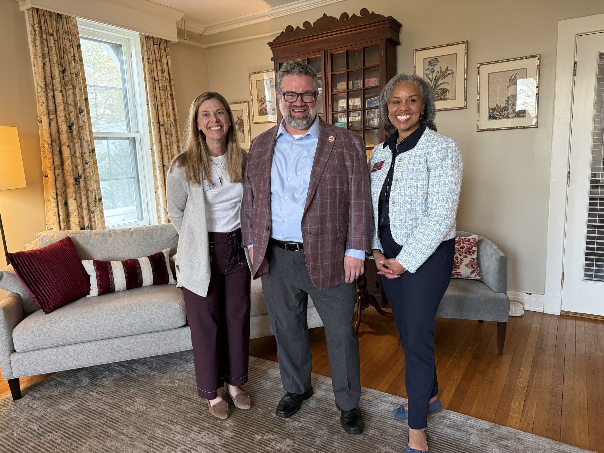 Three people stand together in a living room, smiling for an Inspiration Speaks portrait.