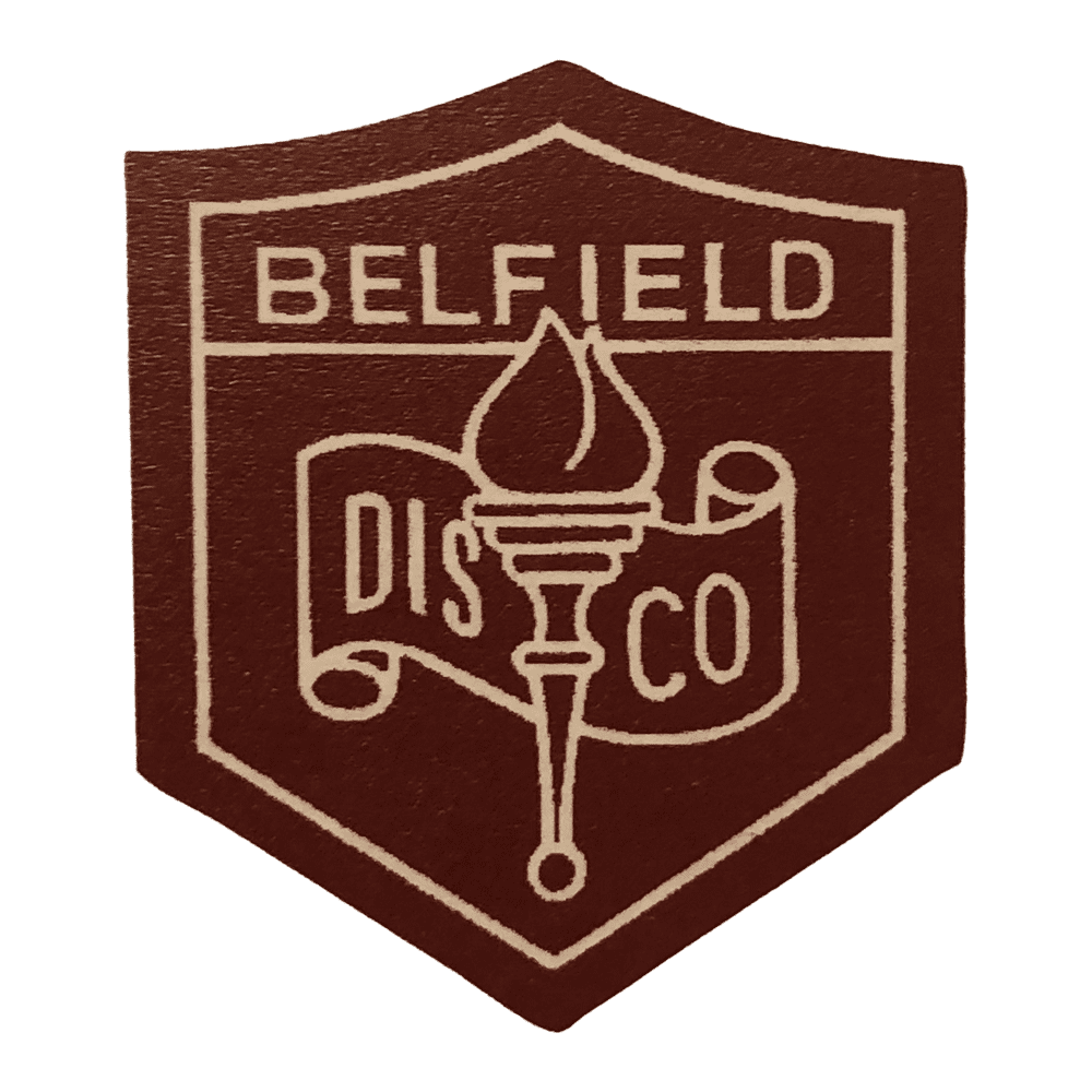 A maroon shield-shaped badge with the word BELFIELD at the top, a torch in the center, and a scroll below displaying the letters DIS CO.